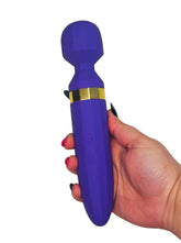 Purple handheld massager with gold accents held in a hand on a white background